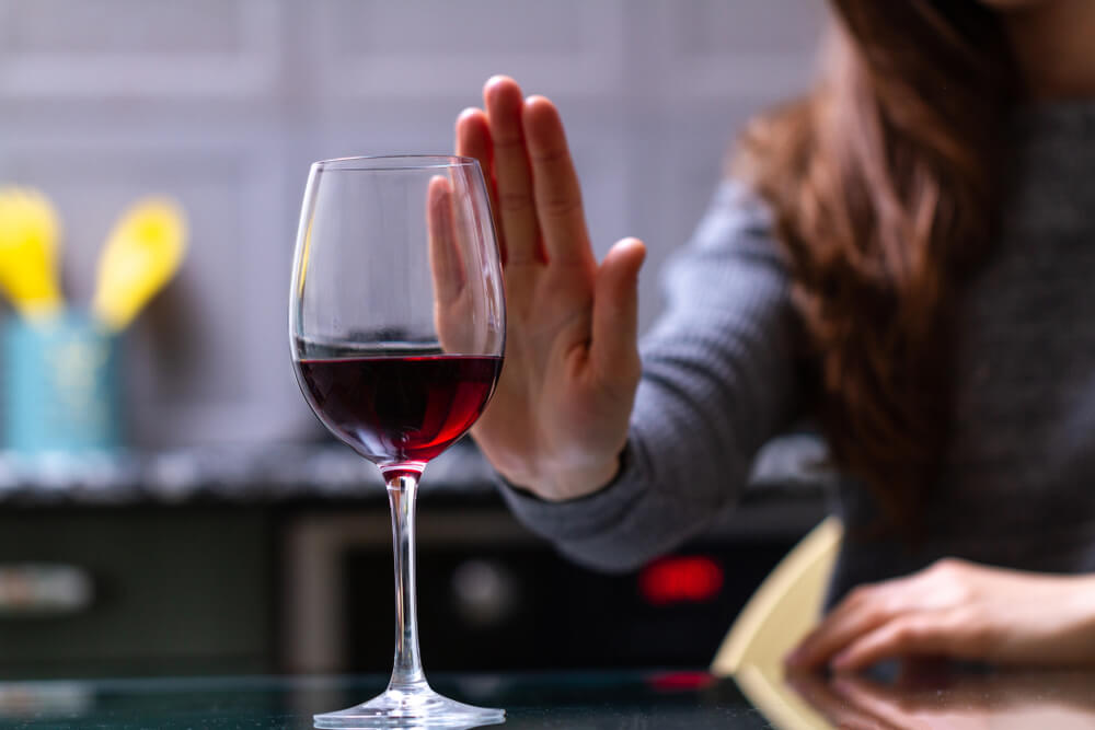 Žena odmítá sklenici červeného vína